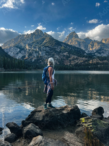 person on the lake looking at mountains 