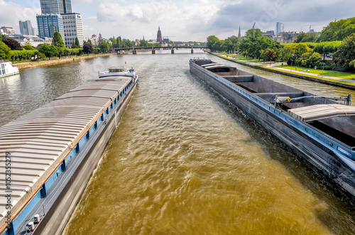 Frankfurt, Germany - July 29, 2024: The view of two barges passing under a bridge over the River Main in Frankfurt
 photo