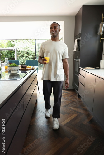 Man holding glass of orange juice in kitchen photo