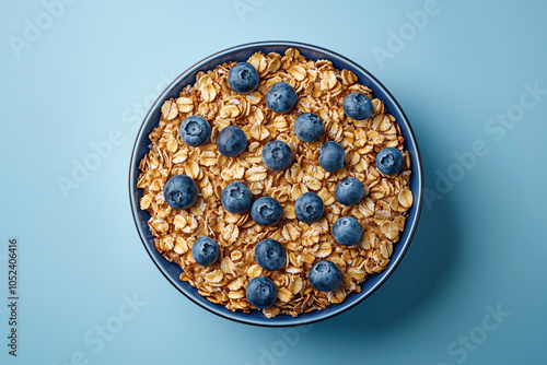 Healthy Homemade Granola with Fresh Blueberries in Blue Ceramic Bowl on Light Blue Background, Top View of Breakfast Oats and Berries, Clean Eating Concept