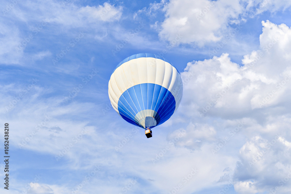 Naklejka premium Colorful hot air balloon flying over blue sky with white clouds