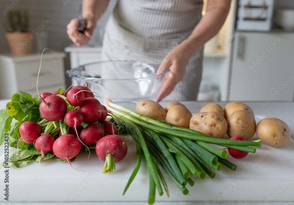 Woman in the kitchen with fresh ingredients for making a healthy potato salad Woman in the kitchen with fresh ingredients for making a healthy potato salad