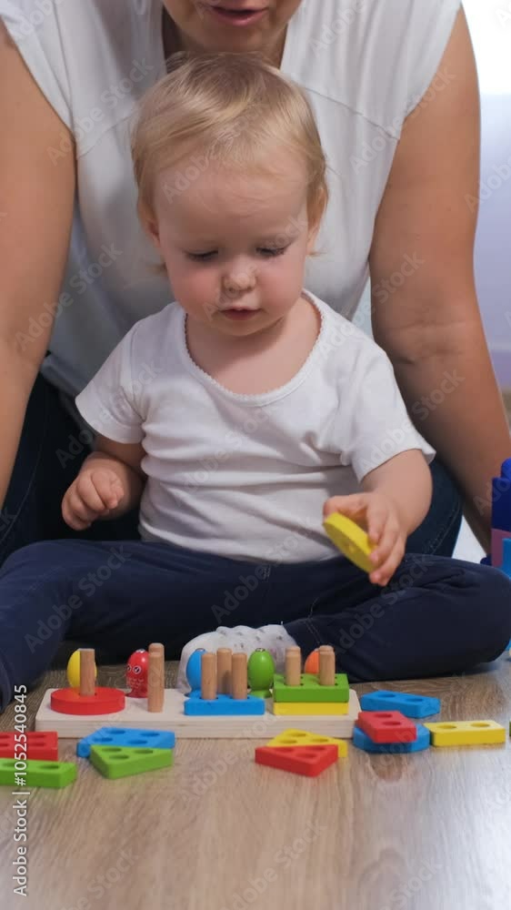 Vertical video. Loving mother engages her baby daughter in playful learning with vibrant educational wooden toys in their cozy nursery at home Vertical video. Loving mother engages her baby daughter in playful learning with vibrant educational wooden toys in their cozy nursery at home