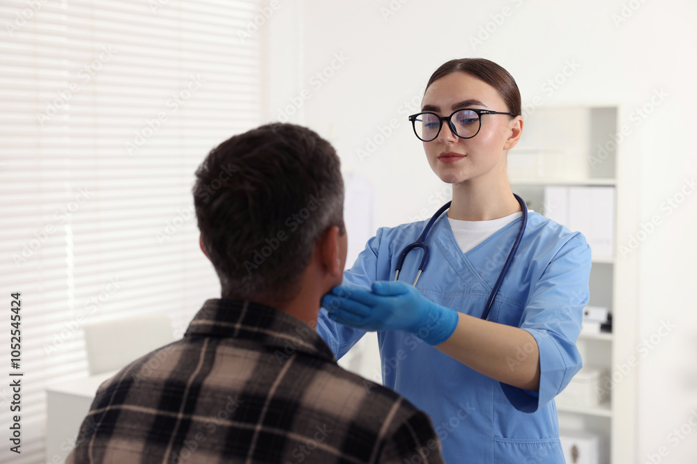 Obraz premium Doctor examining man's throat in clinic during appointment