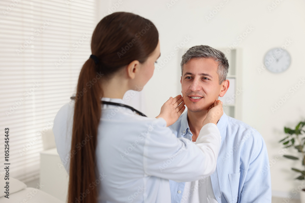 Doctor examining man's throat in clinic during appointment Doctor examining man's throat in clinic during appointment