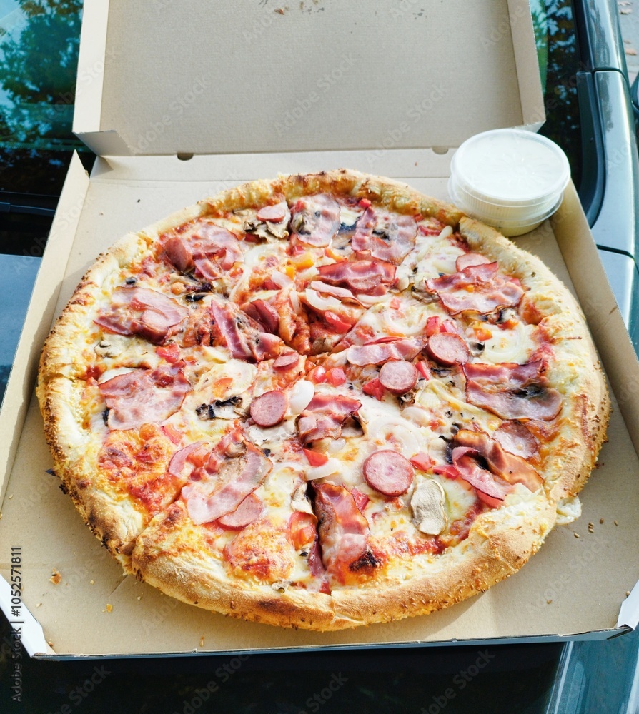 Naklejka premium Duża pizza w kartonie na wynos, kolorowa, smaczna, wypieczona.