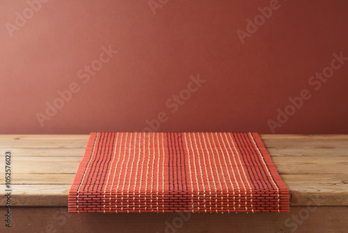 Empty wooden table with bamboo tablecloth over brown wall background.  Kitchen mock up for design and product display