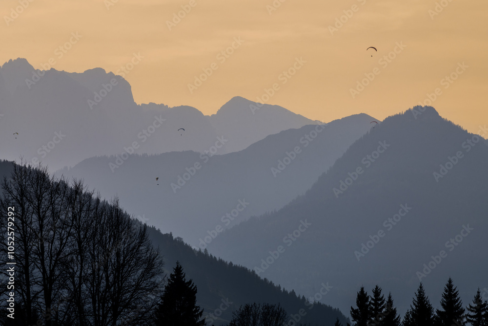 Obraz premium Paragliders silhouetted over the mountains in Reit Im Winkl, Germany.