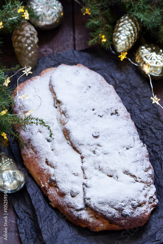 Christmas stollen with dried fruits, nuts and spices, Christmas decorations on a dark wooden background. Rustic style.