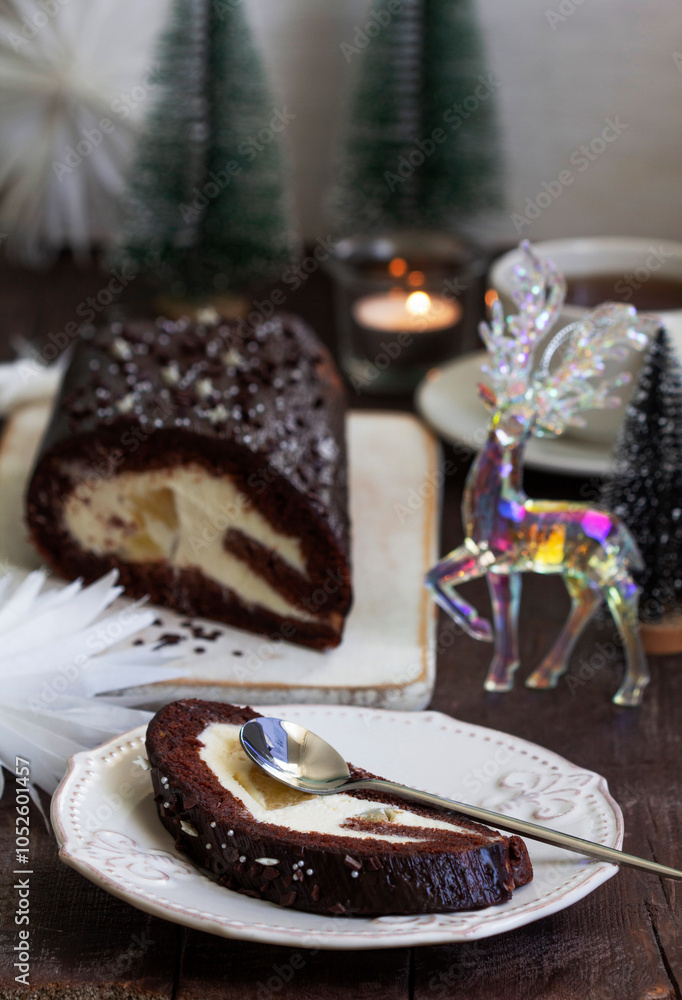 Chocolate roll stuffed with butter cream and pineapple on a Christmas background. Rustic style.