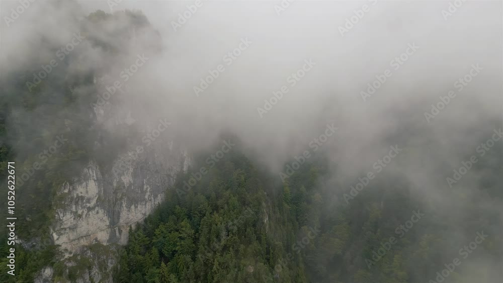 Aerial view of mysterious rocky forest mountains hidden in misty clouds in autumn nature Aerial view of mysterious rocky forest mountains hidden in misty clouds in autumn nature