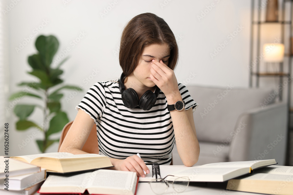 Preparing for exam. Tired student with books at table indoors Preparing for exam. Tired student with books at table indoors