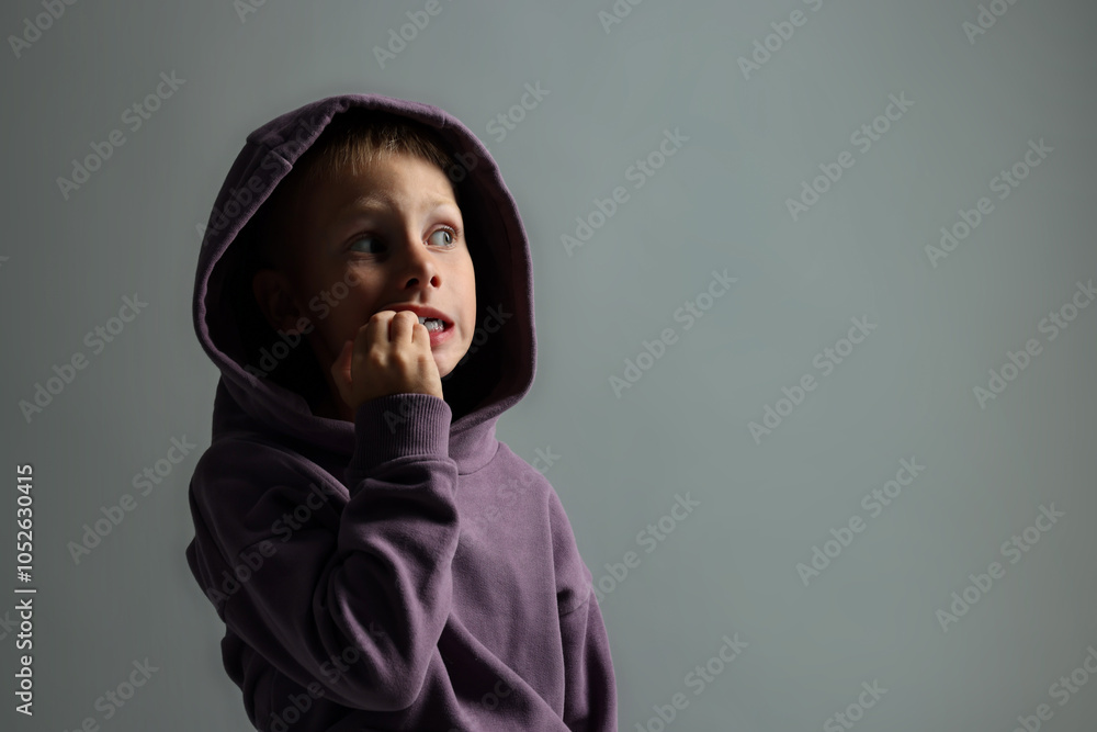 Scared little boy on grey background. Space for text
