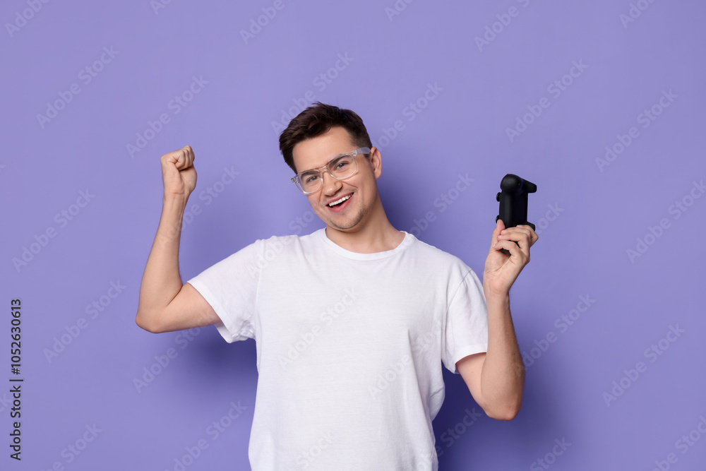 Happy young man with controller on violet background Happy young man with controller on violet background