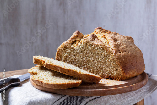 Homemade Irish soda bread cut into pieces and knife on wooden background. photo