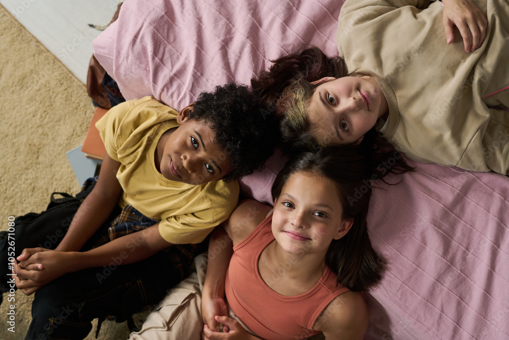 Portrait of three children lying on bed looking straight at camera with a friendly expression. In a cozy indoor setting, each child displays unique hairstyle and clothing. Portrait of three children lying on bed looking straight at camera with a friendly expression. In a cozy indoor setting, each child displays unique hairstyle and clothing.