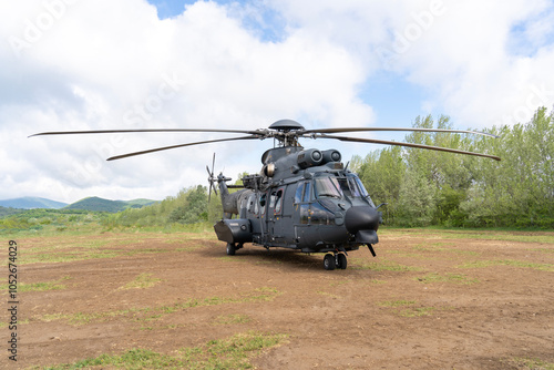 Black painted modern H225M military transport helicopter stationary on the ground