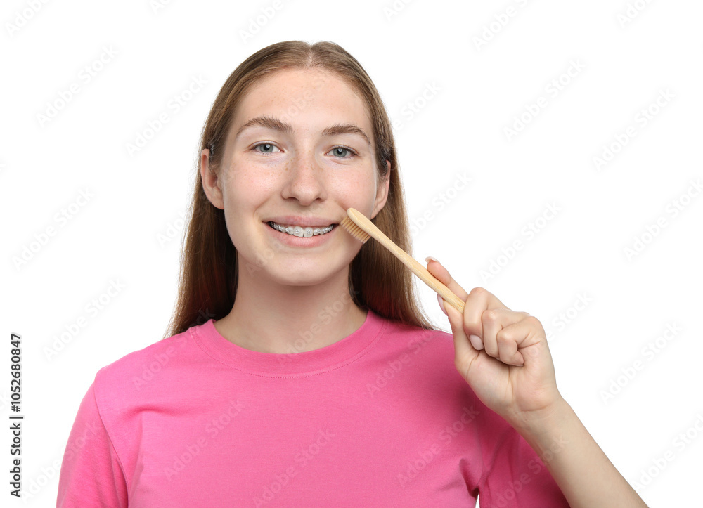 Smiling girl with braces cleaning teeth on white background Smiling girl with braces cleaning teeth on white background