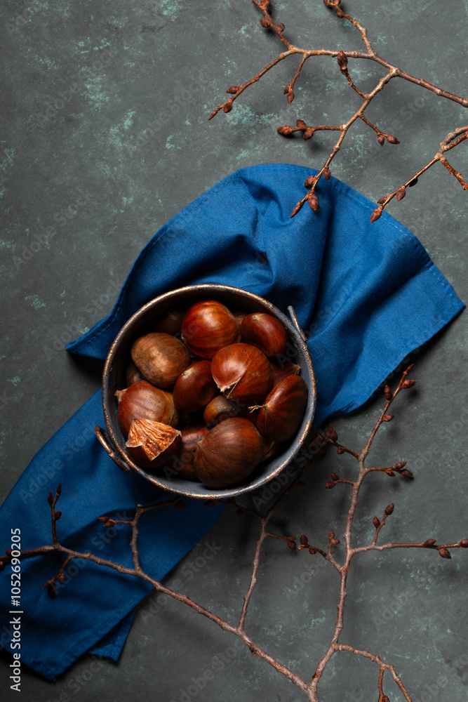 A bowl with edible chestnuts stands on a blue cloth