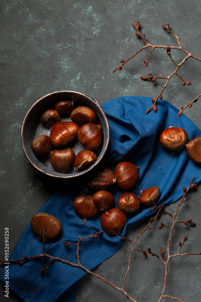 A bowl with edible chestnuts stands on a blue cloth