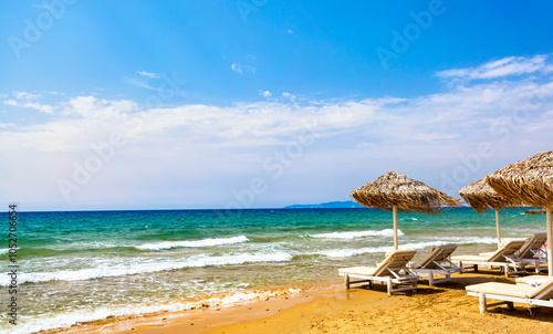 Sun loungers and umbrellas on the sandy beach by the Mediterranean Sea in Greece. Vacation background. Idyllic beach landscape. photo