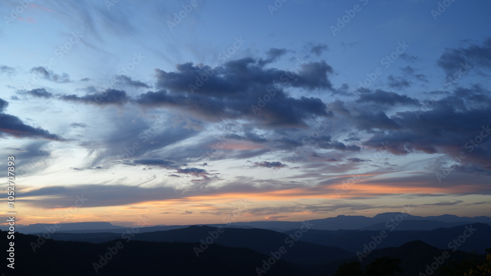 Fototapeta premium breathtaking sunset over rolling hills, showcasing vibrant clouds and serene landscape. colors blend beautifully, creating peaceful atmosphere