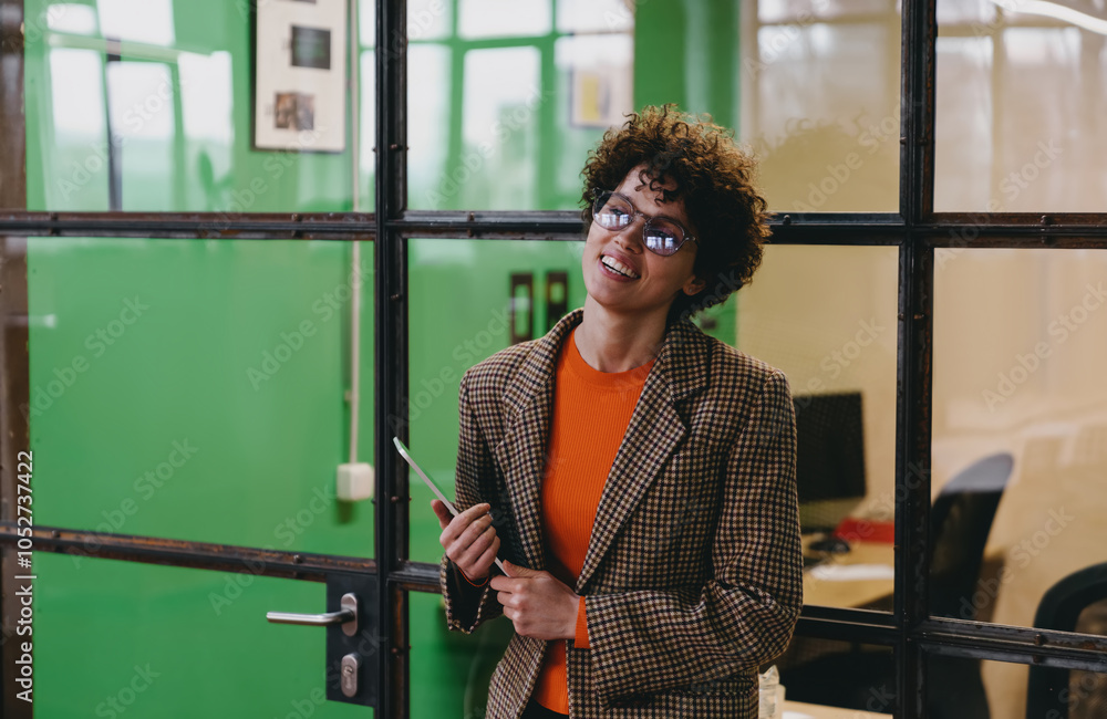 Fototapeta premium Cheerful woman with tablet standing and smiling in office