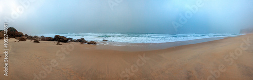 A misty, deserted beach with gentle waves washing over the sandy