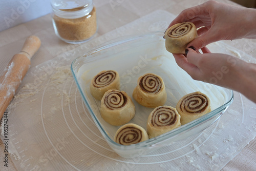 A woman hands putting a piece of roll in a baking dish on a table on a silicone mat photo