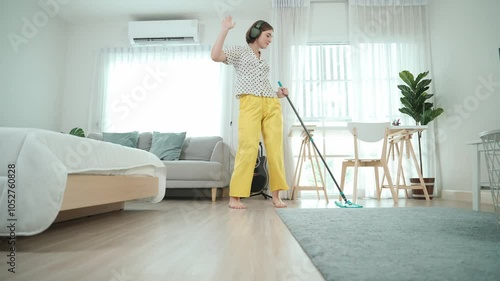 Wallpaper Mural Smart housekeeper with headphone mopping the floor while move to music. Caucasian mother cleaning the living room while using headset listening song. Smiling mom doing housework. Lifestyle. Pedagogy. Torontodigital.ca