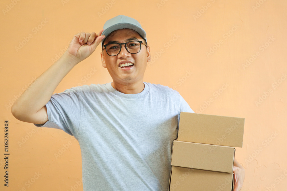 Asian Young delivery man wearing grey shirt on yellow background studio holding package box Asian Young delivery man wearing grey shirt on yellow background studio holding package box
