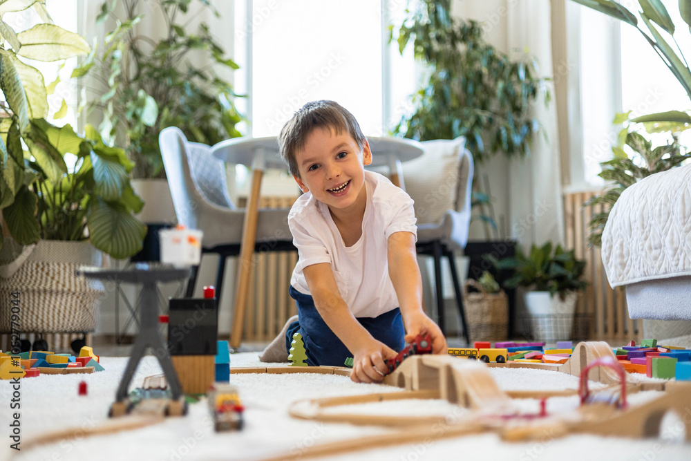 A European child plays with a wooden railway and colored blocks at home. A European child plays with a wooden railway and colored blocks at home.