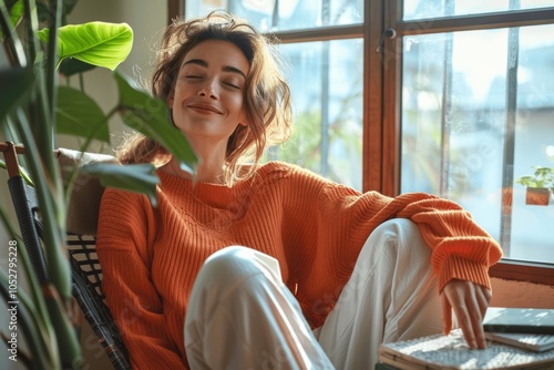 Happy woman meditating on chair at home near window with book and plant photo