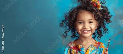 joyful girl with paintbrushes on blue background photo