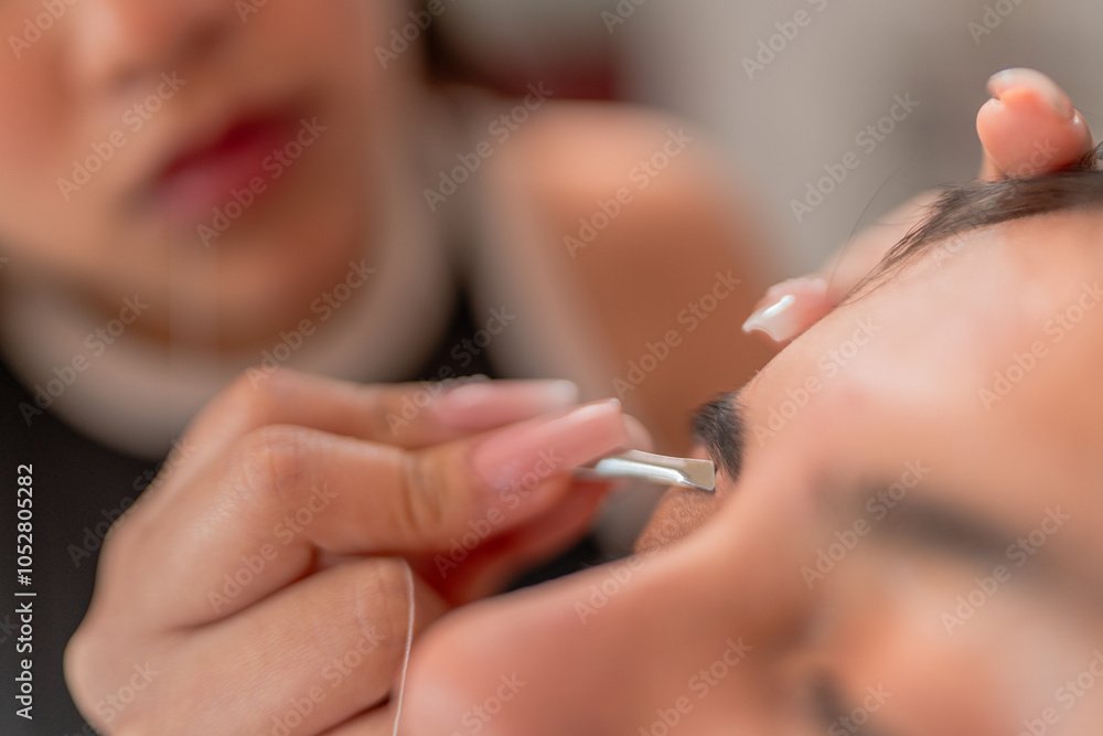 Beautician shaping eyebrows of customer with tweezers Beautician shaping eyebrows of customer with tweezers