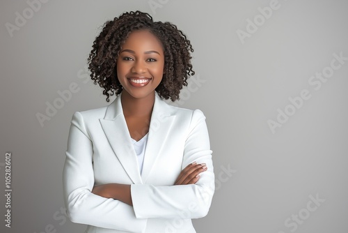 Confident African American businesswoman in white suit smiles warmly in corporate setting against neutral background