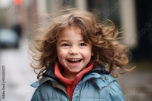 Portrait of a cute little girl with curly hair in the city