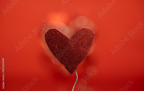 un corazón sostenido por alambre con fondo rojo desenfocado photo