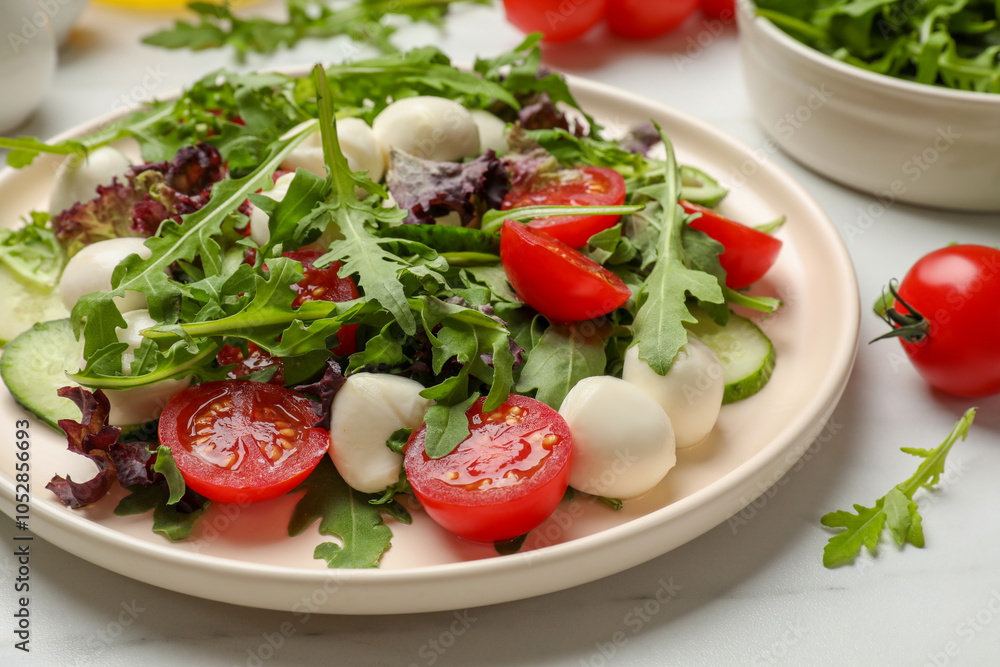 Tasty salad with arugula, lettuce, mozzarella cheese and vegetables on white table, closeup Tasty salad with arugula, lettuce, mozzarella cheese and vegetables on white table, closeup