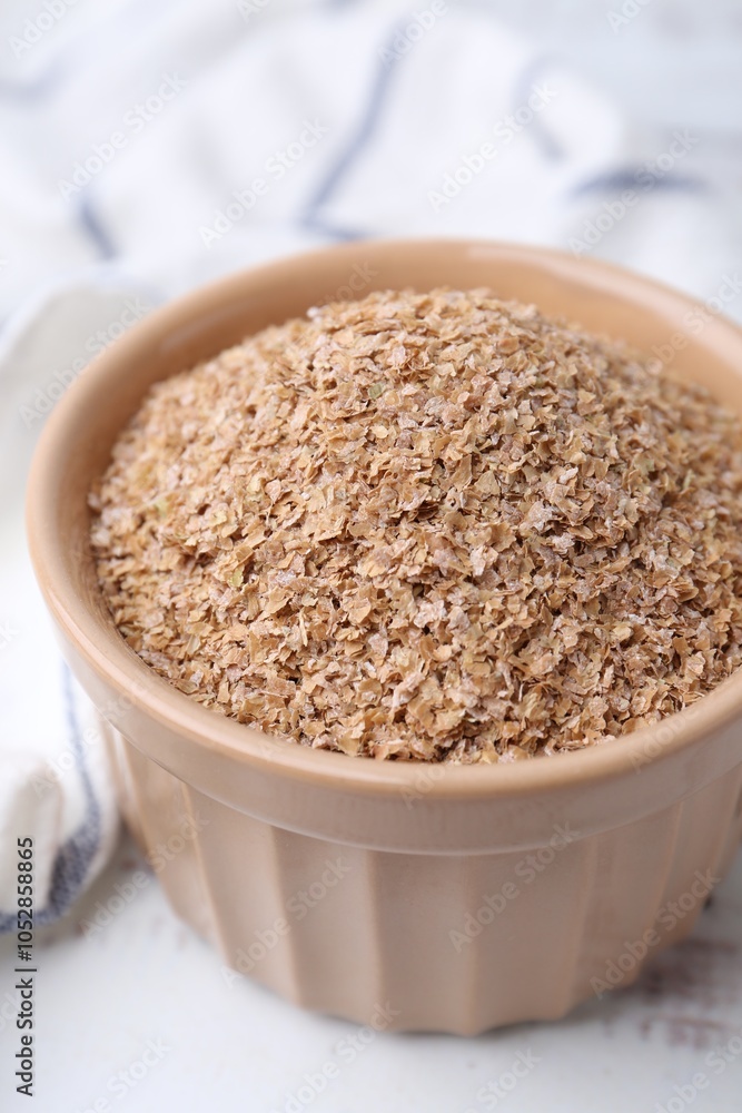 Buckwheat bran in bowl on white table, closeup Buckwheat bran in bowl on white table, closeup
