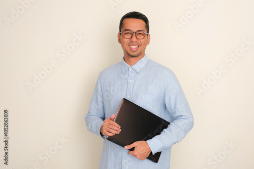 A man smiling confident while holding a laptop photo