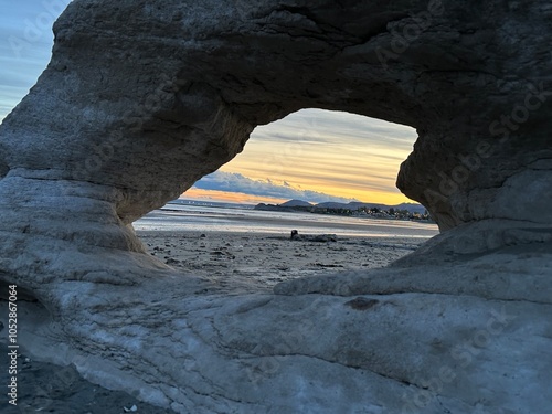 Roca en forma de ventana con atardecer en el mar de fondo 