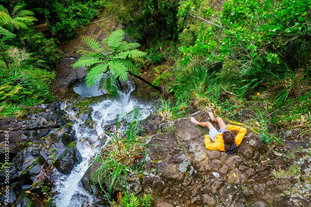 Boy sitting on the edge of a waterfall at the Fairy Falls Walk, Henderson, Auckland, New Zealand. Boy sitting on the edge of a waterfall at the Fairy Falls Walk, Henderson, Auckland, New Zealand.