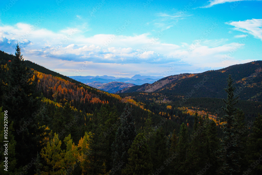 Fototapeta premium Mountain Landscape with Dense Forests and Autumn Colors Under a Blue Sky – Scenic View of Natural Wilderness in Fall