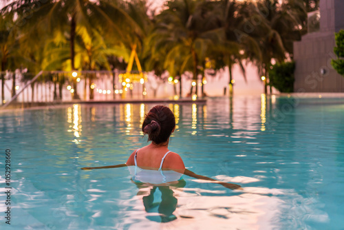 Wall Mural Young woman traveler relaxing and enjoying the sunset by a tropical resort beach