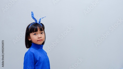 Charming Asian little girl, in a blue dress with a hair band in her head against the photo studio background photo