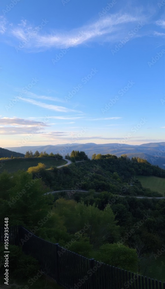 Fototapeta premium a winding road in the mountains with a fence landscape view