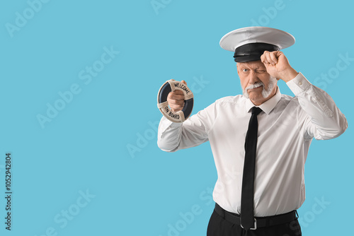 Mature sailor with small ring buoy on blue background photo