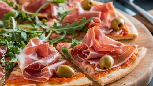 Italian pizza topped with prosciutto, green olives, and fresh arugula close-up