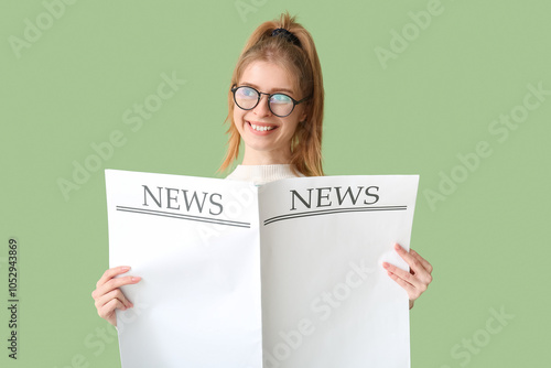 Beautiful young woman with blank newspaper near green wall photo